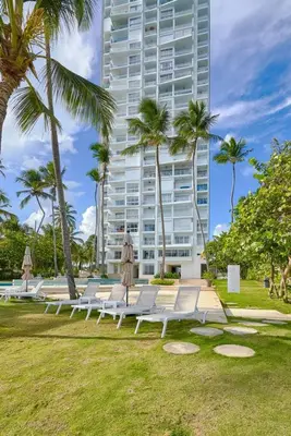 a row of lounge chairs in a park with a tall building at Aquarella Sunset Caribbean Beachfront Gataway in La Puntica de Juan Dolio