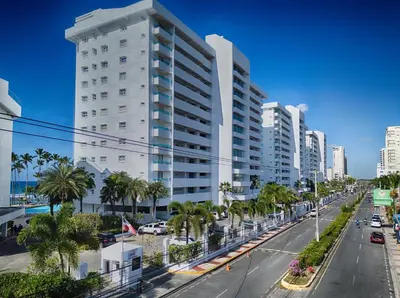 a tall white building on a city street with palm trees at Huge Lux 3br Beachfront Condo Wifi Fast in Paraíso