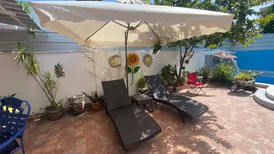 a patio with an umbrella and chairs and plants at Increible Casa Con Piscina! in Los Frailes