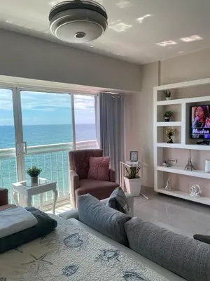 a living room with a bed and a view of the ocean at Hermoso Aparta- Estudio Frente al Mar in Santo Domingo