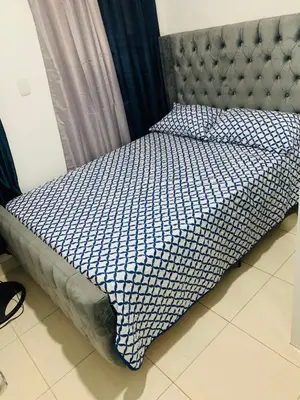 a bed with a blue and white comforter on it at Apartamento Acogedor in San Felipe de Puerto Plata