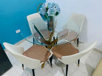 a glass table with four chairs and a vase with flowers at Apartamento Acogedor in San Felipe de Puerto Plata
