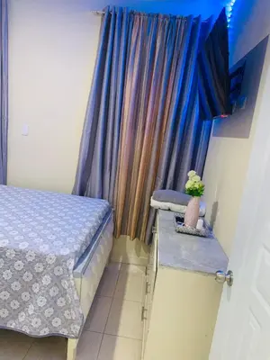 a bedroom with a bed and a window with blue curtains at Apartamento Mariela 2 in San Felipe de Puerto Plata