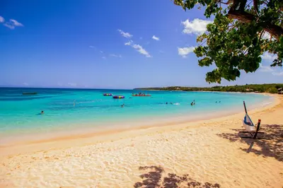 a beach with people swimming in the water at Paradise Island Beach Resort in Punta Rucia