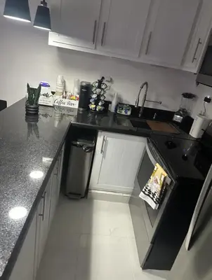 a kitchen with white cabinets and a black counter top at Luxury Apartment Hot Water,AC,WiFi,PS3 in San Felipe de Puerto Plata