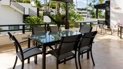 a glass table and chairs on a balcony at Aligio Apart-hotel & Spa - Las Terrenas in Las Terrenas