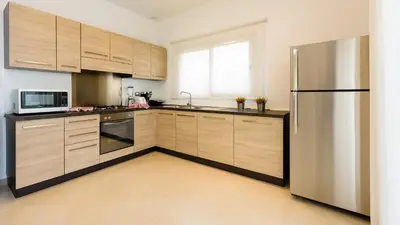 a kitchen with wooden cabinets and a stainless steel refrigerator at Aligio Apart-hotel & Spa - Las Terrenas in Las Terrenas