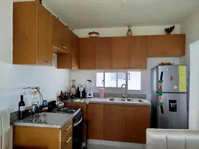 a kitchen with wooden cabinets and a stainless steel refrigerator at Higüey City Home in Higuey