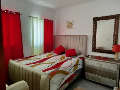 a bedroom with a bed with red curtains and a mirror at Higüey City Home in Higuey