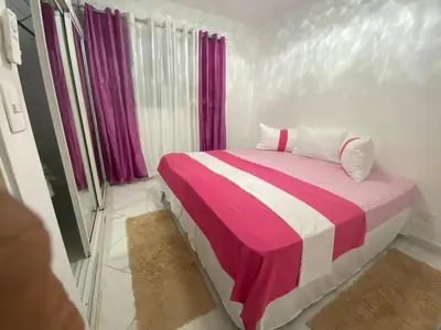 a bedroom with a bed with pink and white sheets at 6B Santiago Harmonic Apt Especially For You in Santiago de los Caballeros