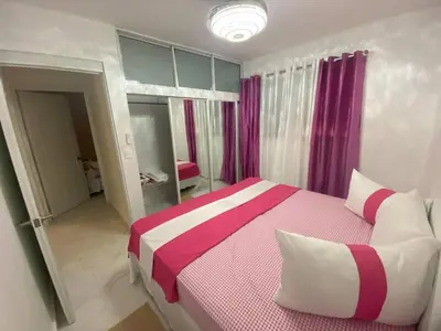 a bedroom with a pink and white bed with purple curtains at 6B Santiago Harmonic Apt Especially For You in Santiago de los Caballeros