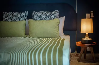 a bed with green pillows and a table with a lamp at Coconut Beach House Playa Bonita Las terrenas Dominican Republic in Las Terrenas