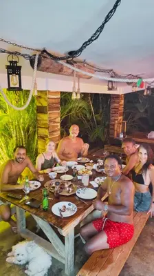 a group of people sitting around a wooden table at Eco Lodges & Camping, Chalets Tropicales, Macao Beach, Bávaro, Punta Cana in Punta Cana