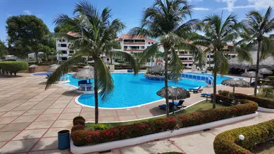 a large swimming pool with palm trees and a building at Aparta Hotel Monte Vista Sosua in Sosúa
