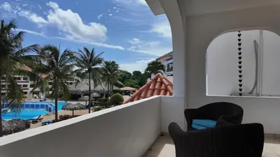 a balcony with a view of a pool and palm trees at Aparta Hotel Monte Vista Sosua in Sosúa