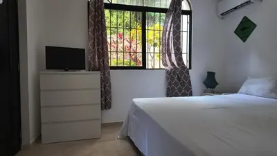 a bedroom with a bed and a tv and a window at Aparta Hotel Monte Vista Sosua in Sosúa