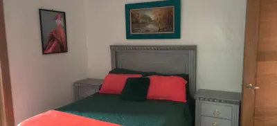 a bedroom with a bed with red and green pillows at Villa Dario in Nagua