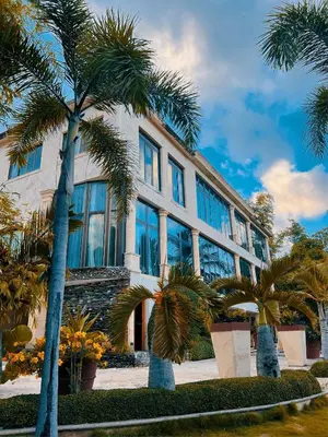 a building with palm trees in front of it at Villa Tesoros del Mar - Luxury Beachfront Villa with Natural Pool, Jacuzzi, Mountain Views, Yoga, BBQ, Wi-Fi, Pet & Family Friendly, Barahona Adventures in El Arroyo