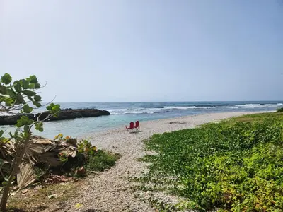 two people standing on a beach near the ocean at Villa Tesoros del Mar - Luxury Beachfront Villa with Natural Pool, Jacuzzi, Mountain Views, Yoga, BBQ, Wi-Fi, Pet & Family Friendly, Barahona Adventures in El Arroyo
