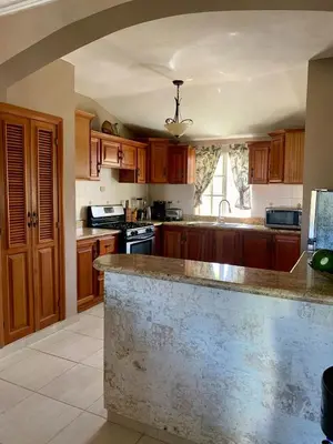 a kitchen with wooden cabinets and a marble counter top at Palm Suites E-6-two-level apartment with a view of the pool in Punta Cana