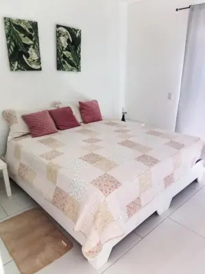 a white bedroom with a large bed with red pillows at Ocean Bliss in Sosúa