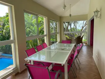 a dining room with a white table and pink chairs at Luxurious Villa in Sosúa + Pool in Sosúa
