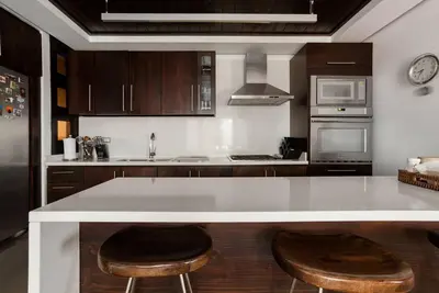 a kitchen with a white counter and two stools at Villa de Estilo Japones in Jarabacoa
