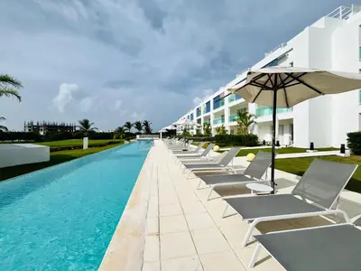 a row of chairs and an umbrella next to a swimming pool at Cana Rock Condos in Punta Cana