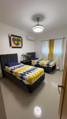 a bedroom with two beds and a table and curtains at Apartamento completo con jacuzzi y gazebo in Santo Domingo