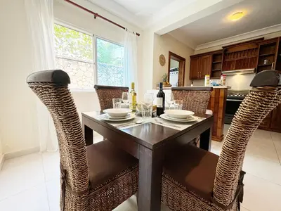 a dining room table with chairs and a bottle of wine at Tropical apartment 2 Bedroon in Los Corales in Punta Cana
