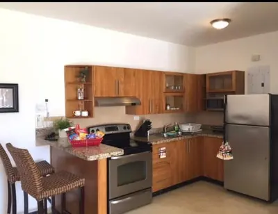 a kitchen with wooden cabinets and a stainless steel refrigerator at Cadaqués, Bayahibe, República Dominicana in Bayahibe