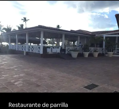 a pavilion with white tables and chairs and palm trees at Cadaqués, Bayahibe, República Dominicana in Bayahibe