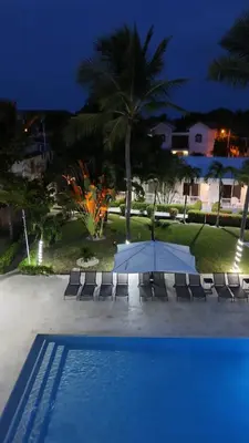 a pool with chairs and an umbrella next to a resort at El Colibri Hotel in Sosúa