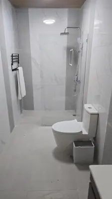 a white bathroom with a toilet and a shower at El Colibri Hotel in Sosúa