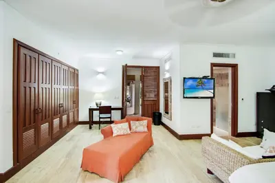 a living room with an orange couch and a tv at Gorgeous villa at Casa de Campo - with large pool, cook, maid and 2 golf carts in La Romana