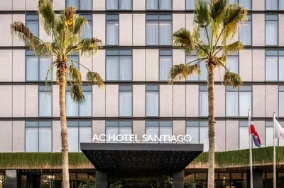 a hotel with palm trees in front of a building at AC Hotel by Marriott Santiago de los Caballeros in Santiago de los Caballeros