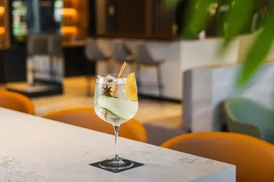 a glass of wine sitting on a table with a lemon slice in it at AC Hotel by Marriott Santiago de los Caballeros in Santiago de los Caballeros