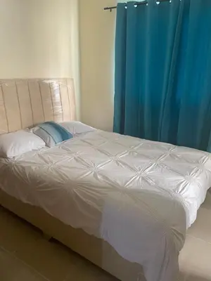 a bed in a bedroom with a blue curtain at Posada del caribe in La Cana