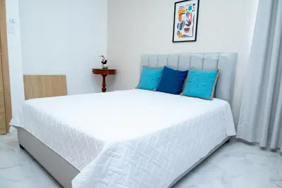a bedroom with a white bed with blue pillows at Apartahotel Señorial in Higuey