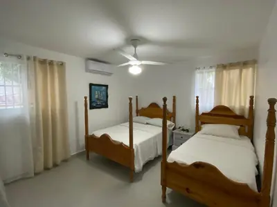 a bedroom with two beds and a ceiling fan at 2 BR & 1WR Suite at Villa Costa Verde near Playa Cofresi, Puerto Plata with a pool, balcony, and a rooftop terrace in San Felipe de Puerto Plata