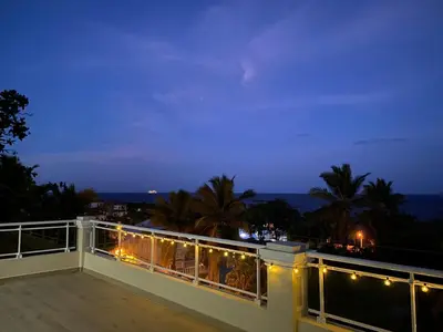 a balcony with a view of the ocean at night at 2 BR & 1WR Suite at Villa Costa Verde near Playa Cofresi, Puerto Plata with a pool, balcony, and a rooftop terrace in San Felipe de Puerto Plata