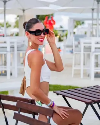 a woman in a white bikini sitting on a bench at Beach Front Apartments by Playa Palmera in Punta Cana