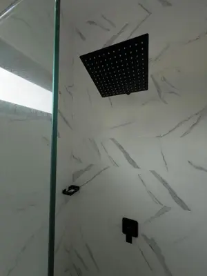 a shower with white marble walls and a black grate at LEVEL suites #7 in Sosúa