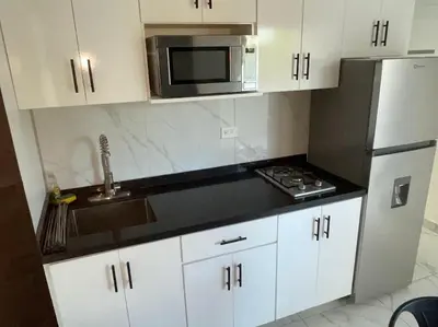 a kitchen with white cabinets and a sink and a microwave at LEVEL suites #7 in Sosúa