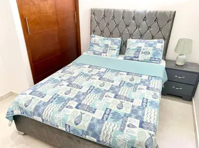 a bed with a quilt and pillows in a bedroom at Beautiful and peaceful 2-bedroom family condo in Juan Dolio