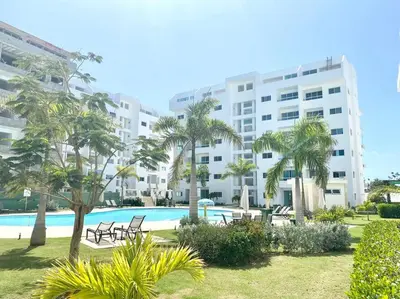 a large apartment building with a pool and palm trees at Beautiful and peaceful 2-bedroom family condo in Juan Dolio