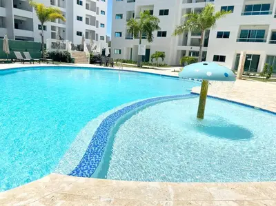 a swimming pool with an umbrella in the middle at Beautiful and peaceful 2-bedroom family condo in Juan Dolio
