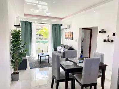 a dining room and living room with a table and chairs at Beautiful and peaceful 2-bedroom family condo in Juan Dolio