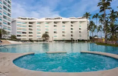 a large hotel with a large pool in front of a building at Beachfront Apartment with Jacuzzi in Juan Pedro