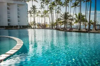 a swimming pool with palm trees and a building at Beachfront Apartment with Jacuzzi in Juan Pedro